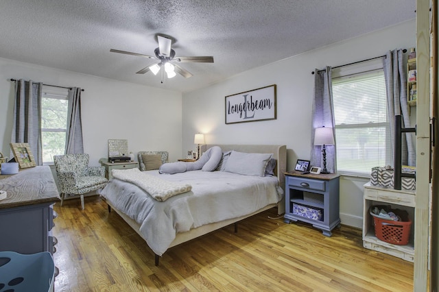 bedroom featuring light wood-style floors, a ceiling fan, and a textured ceiling