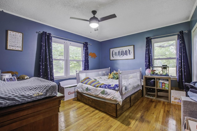 bedroom featuring a ceiling fan, crown molding, a textured ceiling, and hardwood / wood-style flooring