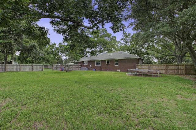 view of yard with a trampoline and a fenced backyard