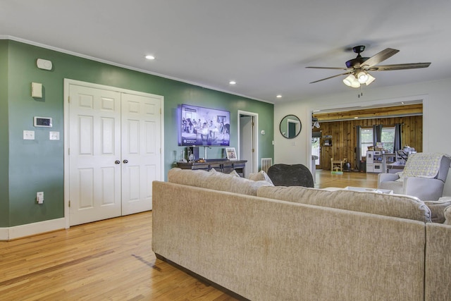 living room featuring baseboards, a ceiling fan, ornamental molding, light wood-style floors, and recessed lighting