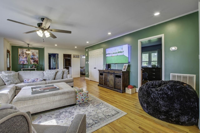 living area featuring crown molding, visible vents, wood finished floors, and recessed lighting