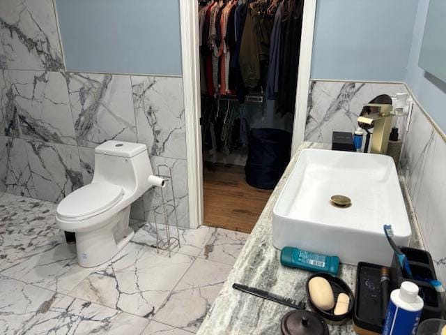 bathroom featuring toilet and tile walls