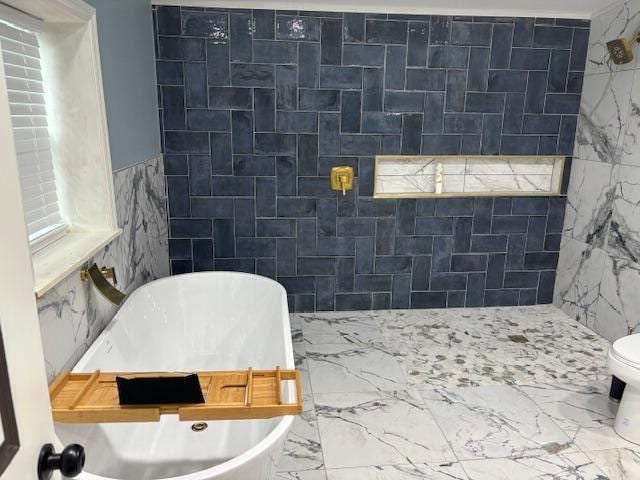 bathroom featuring a tub, tile walls, and toilet