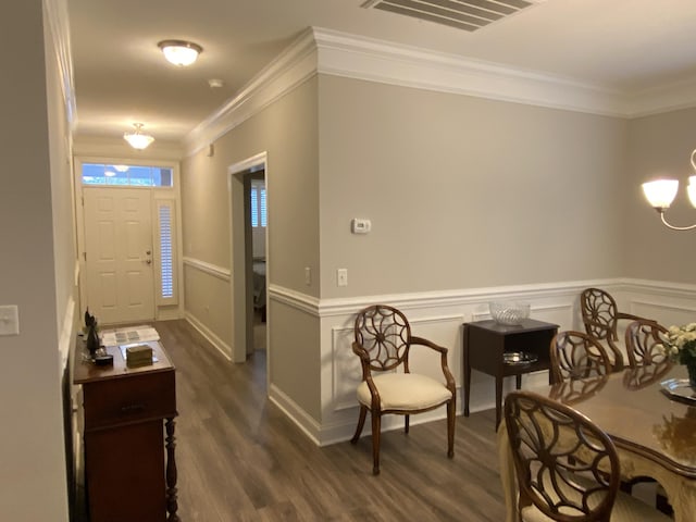 entrance foyer with dark hardwood / wood-style floors, an inviting chandelier, and crown molding