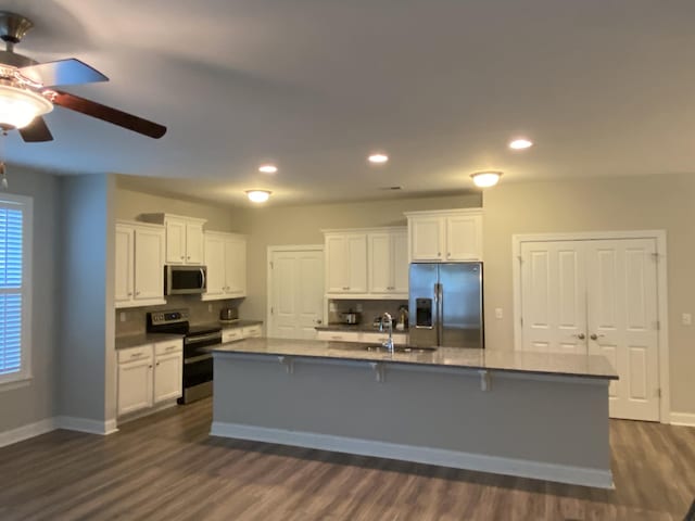 kitchen featuring white cabinets, appliances with stainless steel finishes, and an island with sink