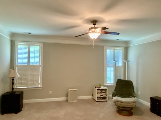 living area with ceiling fan, crown molding, and light carpet