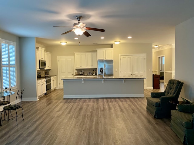 kitchen with a breakfast bar, white cabinetry, a kitchen island with sink, and appliances with stainless steel finishes