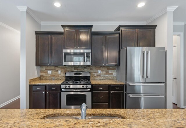 kitchen with backsplash, stainless steel appliances, dark brown cabinetry, ornamental molding, and sink