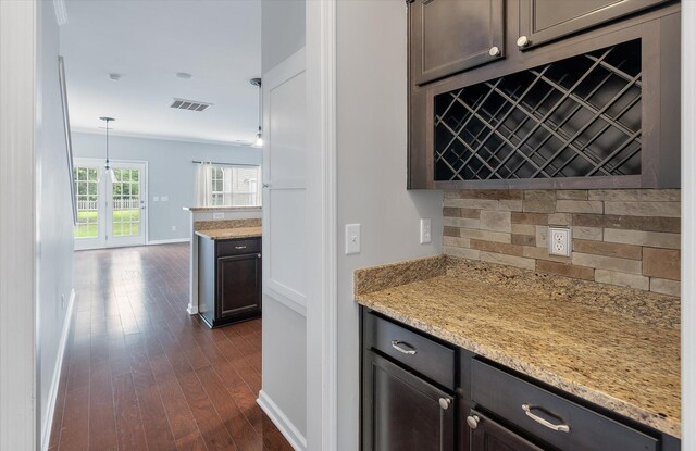 kitchen featuring light stone countertops, hanging light fixtures, dark brown cabinetry, and dark hardwood / wood-style flooring