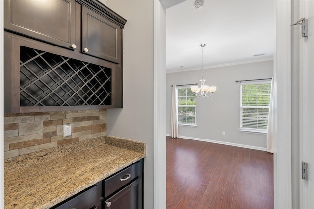 kitchen with dark brown cabinets, a notable chandelier, crown molding, and dark hardwood / wood-style floors