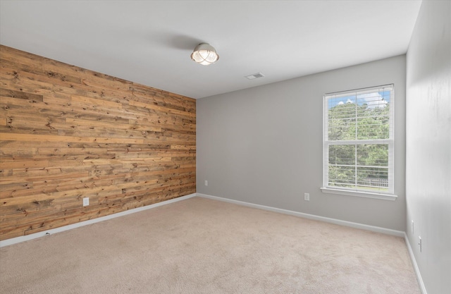 spare room featuring light carpet and wooden walls