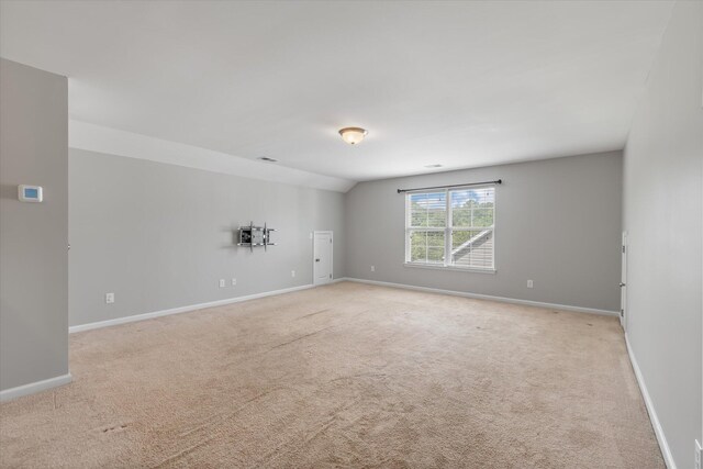 carpeted spare room featuring vaulted ceiling