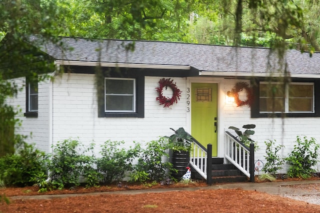 single story home featuring brick siding and a shingled roof