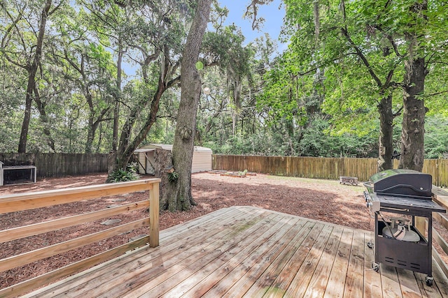 deck featuring a storage shed, a fenced backyard, an outdoor structure, and area for grilling