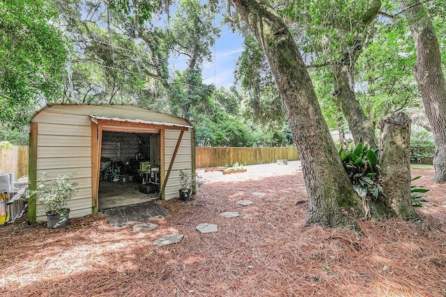 view of yard featuring a storage shed, fence, and an outbuilding