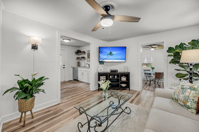 living room featuring ceiling fan, light wood-style floors, plenty of natural light, and crown molding