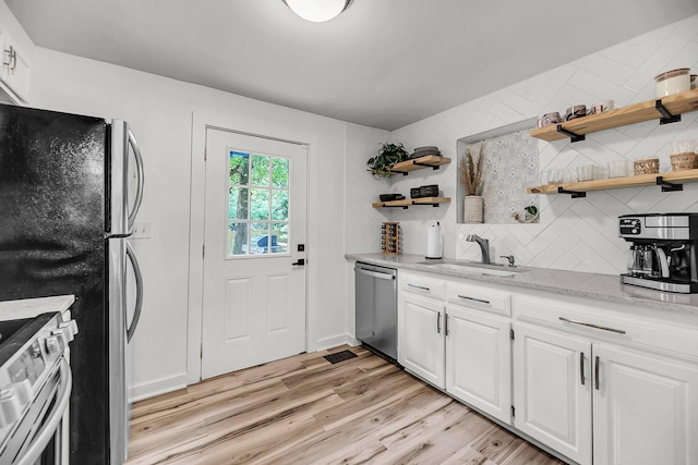 kitchen featuring stainless steel appliances, open shelves, a sink, and tasteful backsplash