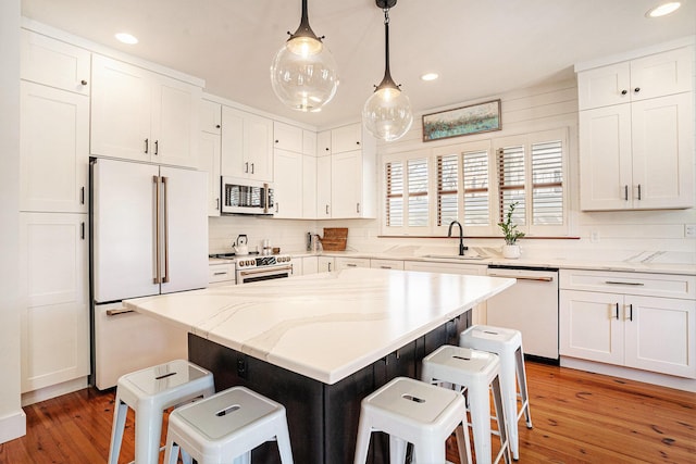 kitchen with a center island, white cabinets, white appliances, and decorative light fixtures