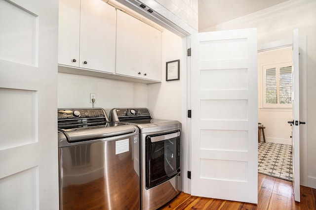 clothes washing area featuring cabinets, wood-type flooring, and washer and dryer