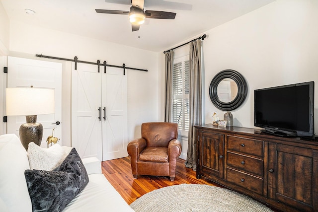 interior space with ceiling fan, wood-type flooring, and a barn door