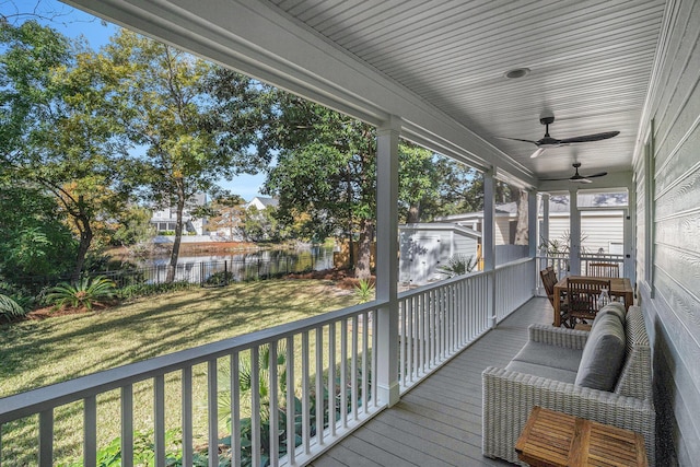 wooden deck with ceiling fan, a storage unit, an outdoor living space, and a lawn