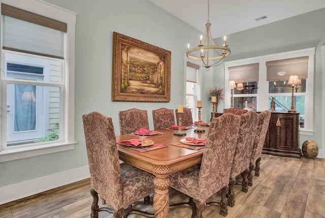 dining space with wood-type flooring, a healthy amount of sunlight, and a chandelier