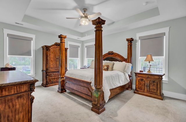 bedroom with multiple windows, ceiling fan, and a raised ceiling