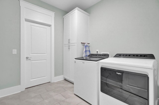 clothes washing area featuring washing machine and clothes dryer and cabinets