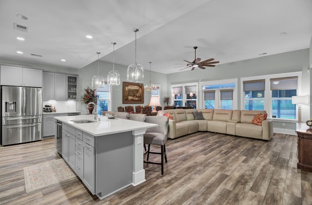 kitchen featuring stainless steel appliances, hardwood / wood-style flooring, sink, backsplash, and a kitchen island with sink