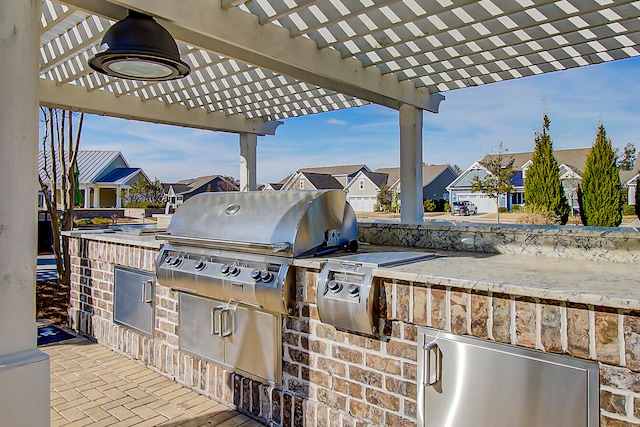 view of patio with area for grilling, a grill, and a pergola