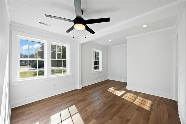 empty room featuring visible vents, baseboards, dark wood-style floors, and crown molding