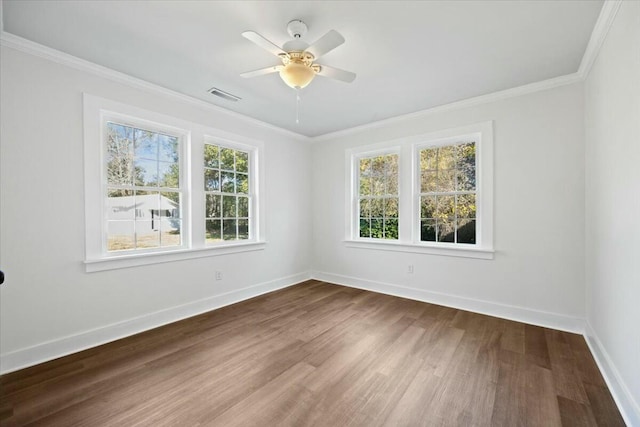 empty room with visible vents, a healthy amount of sunlight, crown molding, and dark wood-type flooring