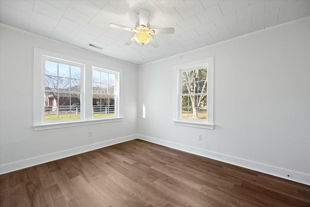 empty room with crown molding, baseboards, and visible vents