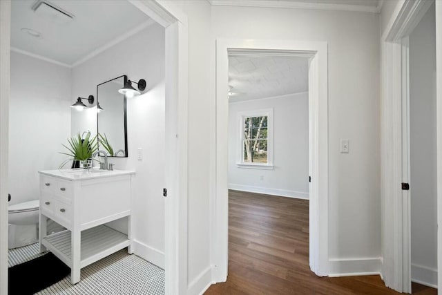 hallway featuring baseboards, wood finished floors, and crown molding