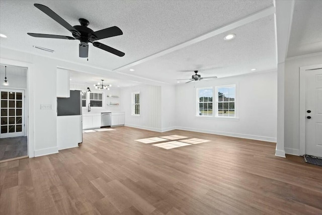 unfurnished living room with visible vents, ceiling fan with notable chandelier, a textured ceiling, and light wood-style floors