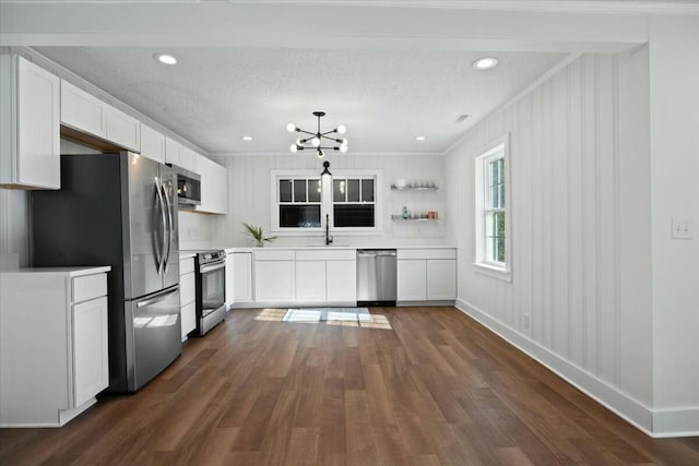 kitchen featuring a notable chandelier, a sink, dark wood finished floors, stainless steel appliances, and white cabinets