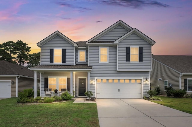 view of front of home featuring covered porch, a garage, and a yard