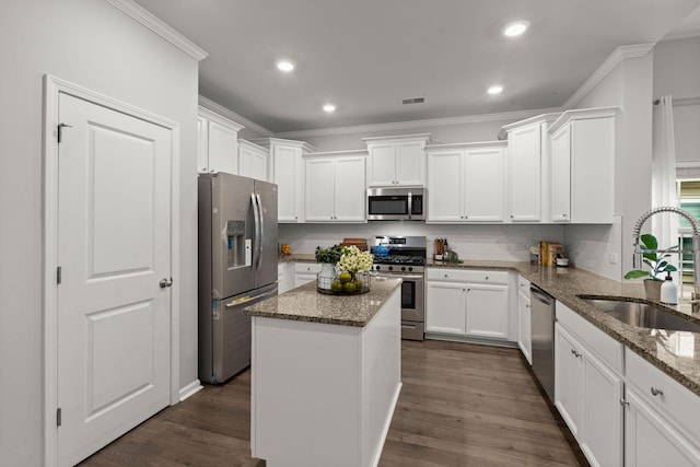 kitchen featuring white cabinets, sink, light stone countertops, a kitchen island, and stainless steel appliances