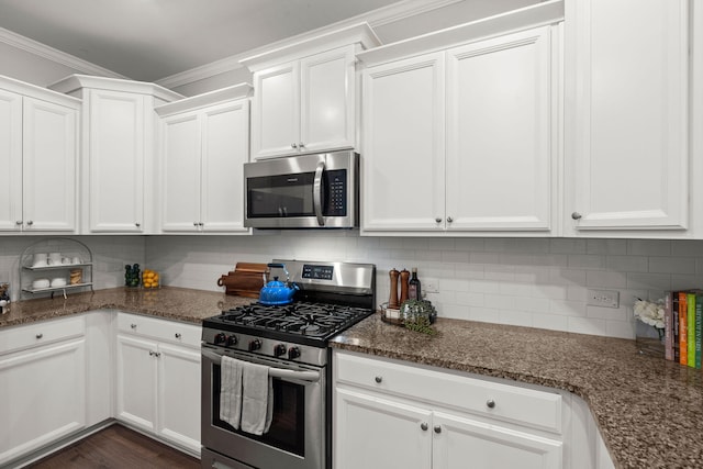 kitchen with decorative backsplash, stainless steel appliances, white cabinetry, and dark stone countertops