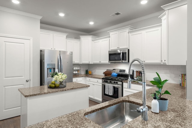 kitchen with light stone countertops, white cabinets, stainless steel appliances, and a kitchen island