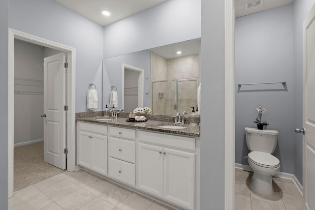 bathroom featuring tile patterned flooring, vanity, toilet, and walk in shower