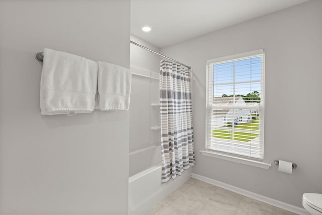 bathroom featuring plenty of natural light, shower / bath combination with curtain, and toilet