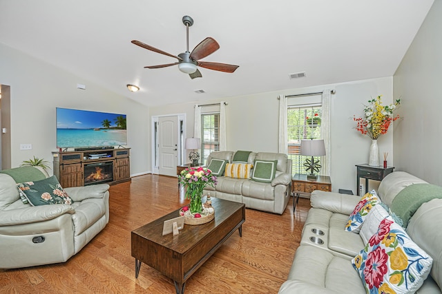 living room with ceiling fan, light hardwood / wood-style floors, and vaulted ceiling