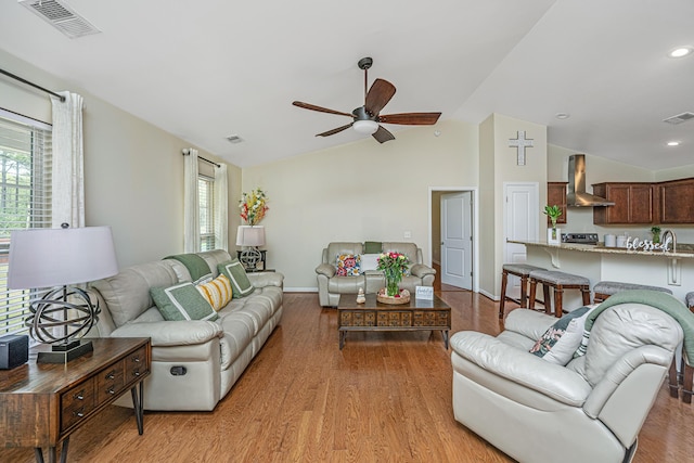 living room featuring ceiling fan, plenty of natural light, vaulted ceiling, and light wood-type flooring