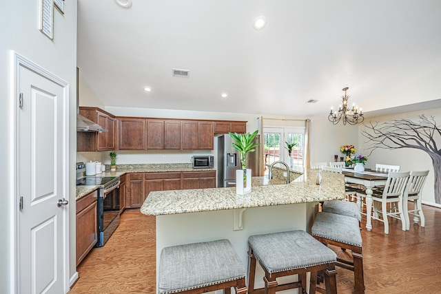 kitchen featuring stainless steel appliances, a kitchen island with sink, light hardwood / wood-style flooring, a chandelier, and hanging light fixtures