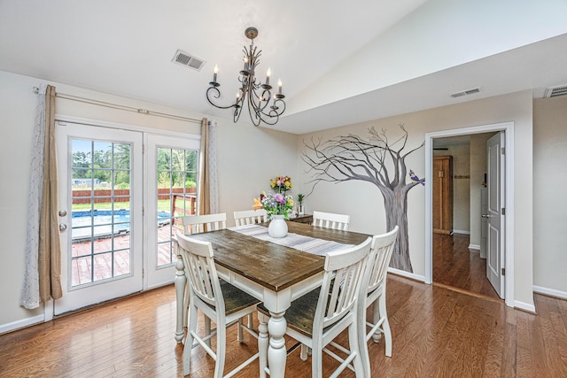 dining space featuring a notable chandelier, wood-type flooring, and lofted ceiling