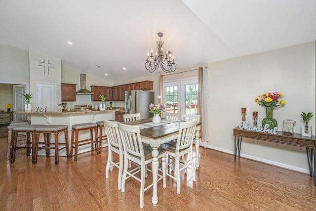 dining room with light hardwood / wood-style floors, lofted ceiling, and a chandelier