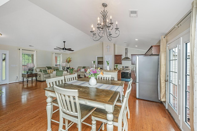 dining space with plenty of natural light, light hardwood / wood-style floors, lofted ceiling, and ceiling fan with notable chandelier