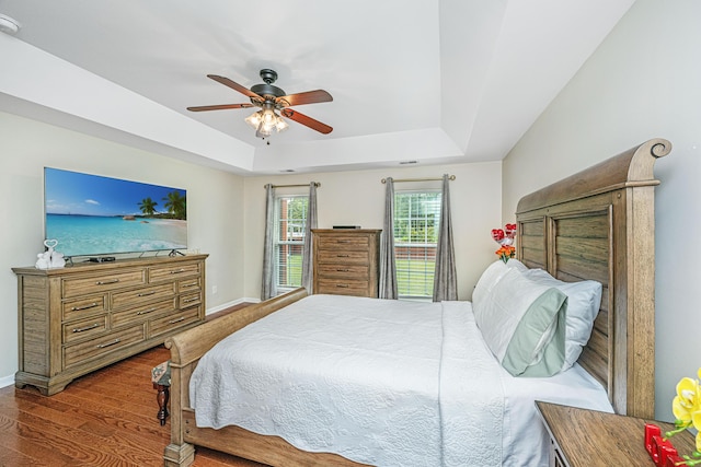 bedroom featuring wood-type flooring, a tray ceiling, and ceiling fan