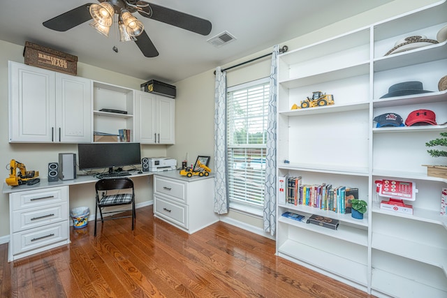 home office featuring ceiling fan, built in desk, and dark hardwood / wood-style floors